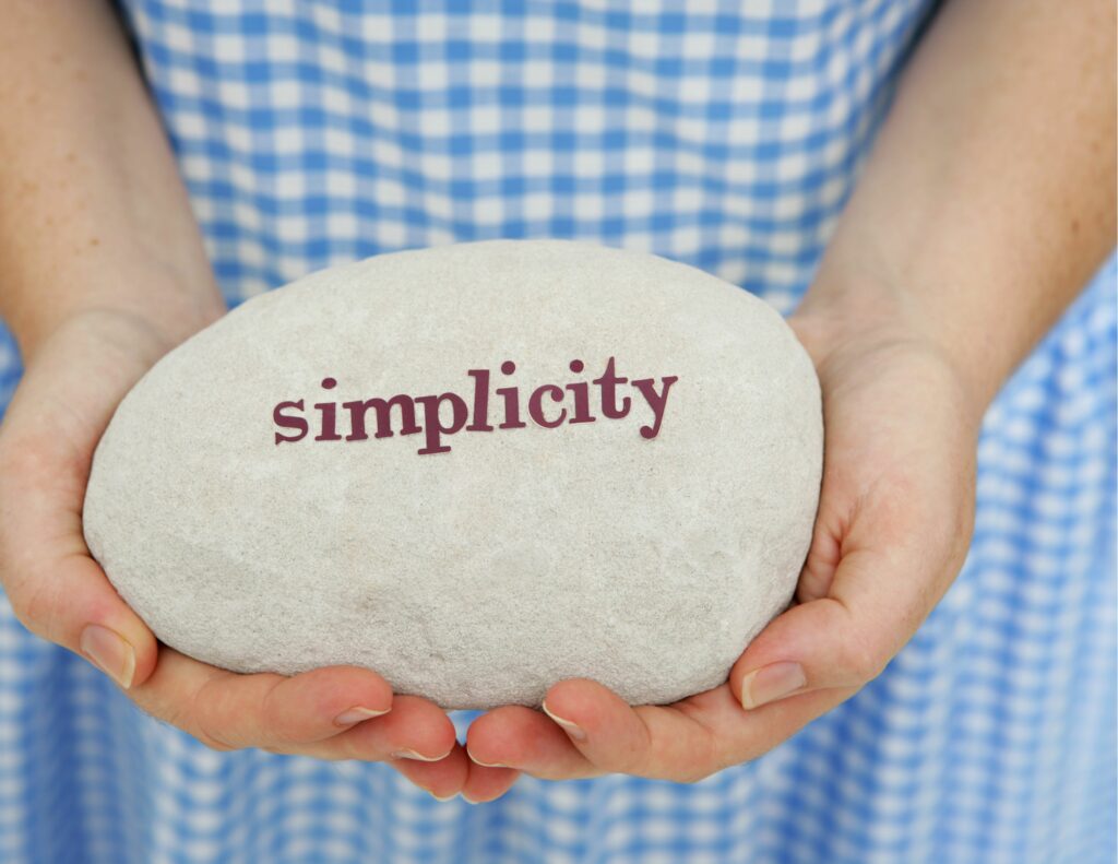 girl holding a rock that says "Simplicity" Less is More